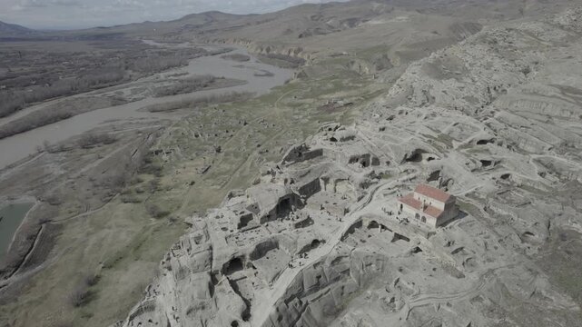 High-altitude aerial view of the Uplistsuli Church of the Prince in Uplistsikhe, an ancient rock-hewn town near Gori, Georgia, highlighting historic stone architecture.