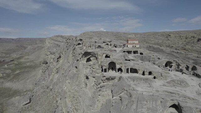 High-altitude aerial view of the Uplistsuli Church of the Prince in Uplistsikhe, an ancient rock-hewn town near Gori, Georgia, highlighting historic stone architecture.