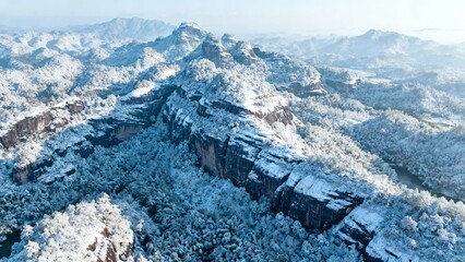 Snow-covered mountain landscape with forested slopes and rocky cliffs under clear sky