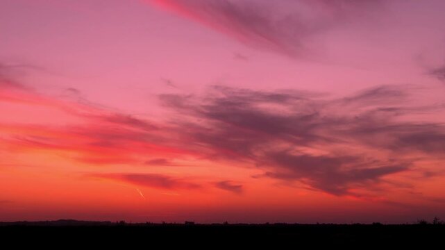 Colorful amazing sunset sky shining sun with rays and beams sunlight horizon colored clouds in the field fast time lapse. Evening bright color twilight sky sun clouds, sunset meadow background 4K