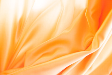 Obraz premium Primer plano de tela de satén naranja con pliegues suaves, reflejos brillantes y textura fluida.sensualidad y movimiento, simbolizando elegancia, suavidad y expresividad textil.