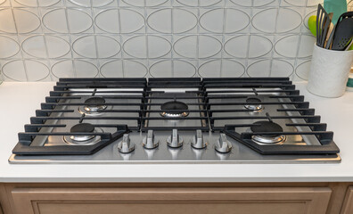 Modern gas cooktop installed in a kitchen with a stylish backsplash and multiple burners for cooking meals