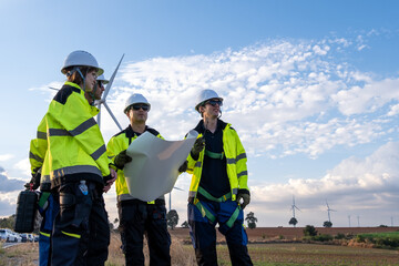 Engineers discuss plans at a wind farm site during the afternoon with wind turbines in the background