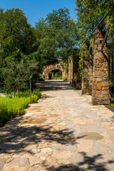 A stone pathway leads to an archway in Lady Bird Johnson wildlife center in Austin Texas Lush greenery and trees surround the path
