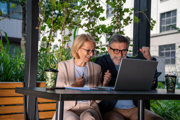 Excited female and male professionals reacting to positive business outcomes