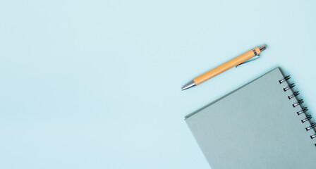 Spiral green notebook and wooden pen on blue background. Copy space. Business, school.