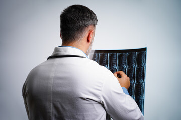 Physician reviewing spinal MRI results from behind with patient in clinic