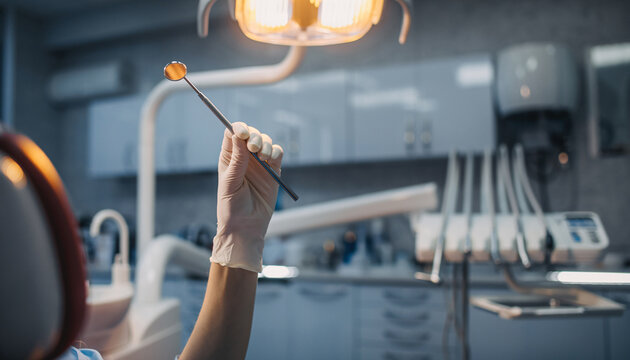 Dentist holding dental tool under bright light in modern clinic