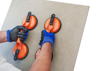 A construction worker holds a ceramic tile with a suction cup lifter, isolated against a free PNG background. Concept for laying ceramic tiles.