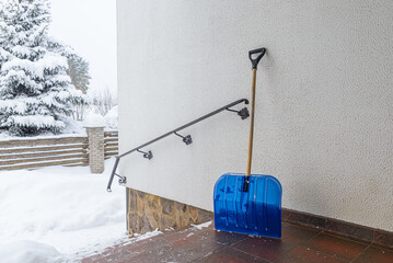 A large shovel for clearing snow from the porch of a residential building in winter