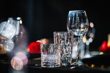 Serving, setting for couple, Valentine's Day evening, for surprise marriage proposal. Plate and wineglass, champagne glasses, black napkin. Restaurant interior. Romantic date at night. Romantic dinner