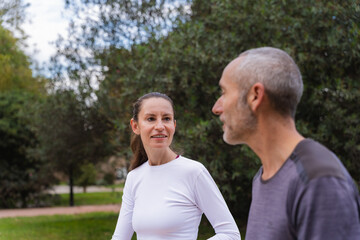 Obraz premium Two friends over forty talking while pausing during a park workout