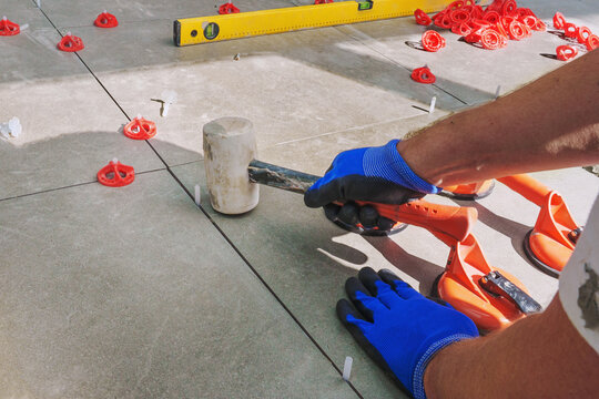 Laying tiles concept. Tiler, spatula and glue when laying tiles with close up hands.