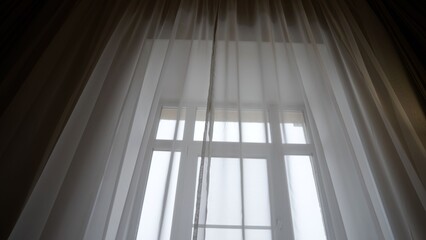 Sheer white curtains covering window diffusing morning light