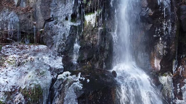 Cascade et rivi&egrave;re traversant un paysage montagneux enneig&eacute; et gel&eacute;. Vid&eacute;o 4K 