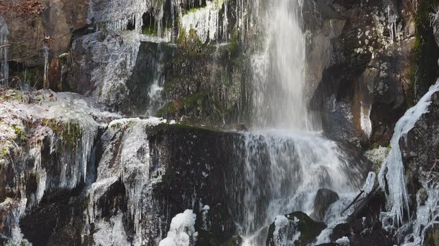 Cascade et rivi&egrave;re traversant un paysage montagneux enneig&eacute; et gel&eacute;. Vid&eacute;o 4K 