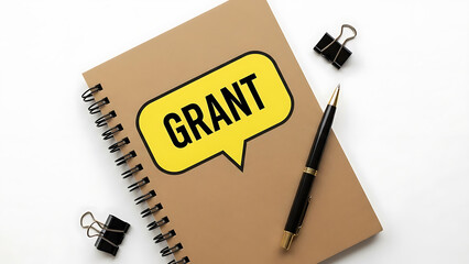 A spiral notebook with a yellow speech bubble saying grant and a pen on a white background