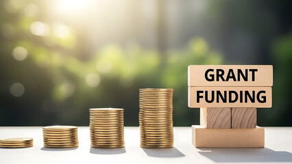 Stacks of coins with grant funding text on a white table outdoors