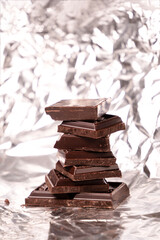 A stack of dark chocolate on a silver foil background.