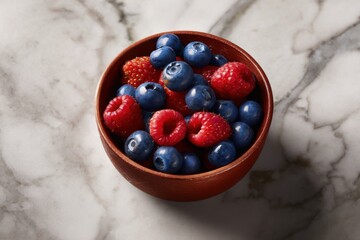 A bowl filled with fresh blueberries and raspberries sits on a marble surface, showcasing vibrant colors and textures.