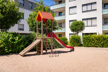 Playground Structure With Slide and Climbing Area Near Residential Buildings in Sunny Weather During the Daytime