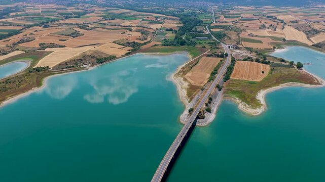Aerial view of Lake Polyfytos in Greece with a curved bridge,