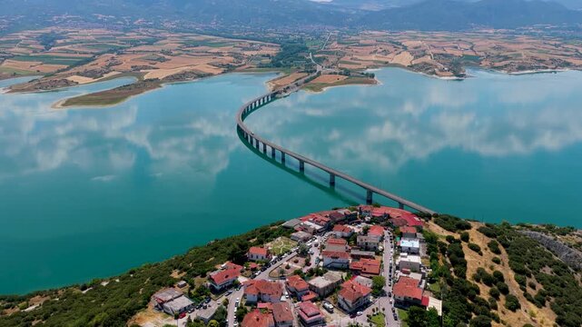 Aerial view of Lake Polyfytos in Greece with a curved bridge,