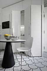 Close-up of a modern wooden dining table and chair against a white lacquered kitchen cabinet.