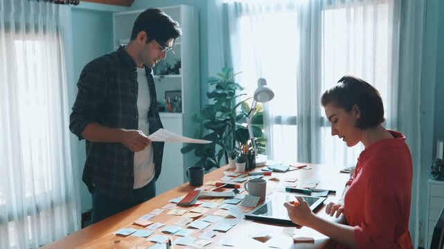 Top view of smart designer holding color palette while project manager looking at design and choosing color for program. Professional businesswoman taking a note while design creative logo. Symposium.