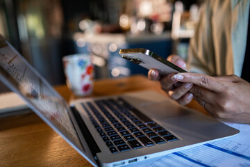 Person using smartphone and laptop at home workspace