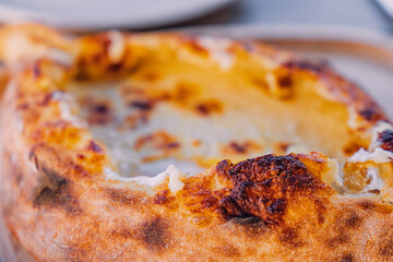 Khachapuri Adjaruli, a traditional Georgian cheese bread, featuring a boat shaped dough filled with melted cheese, fresh from the oven