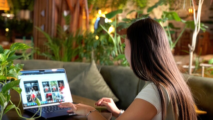 Side view of asian female freelancer working on laptop in a cozy green cafe. Remote work, digital lifestyle, creativity, inspiration, online browsing, cafe coworking and modern urban living concept.