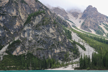 Emerald alpine lake framed by forest and towering Dolomites cliffs