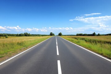 Endless Road Under Clear Blue Sky with Lush Greenery on Both Sides
