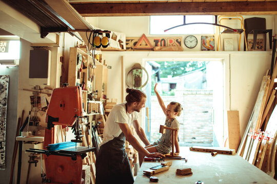 Father teaching daughter woodworking in home garage workshop