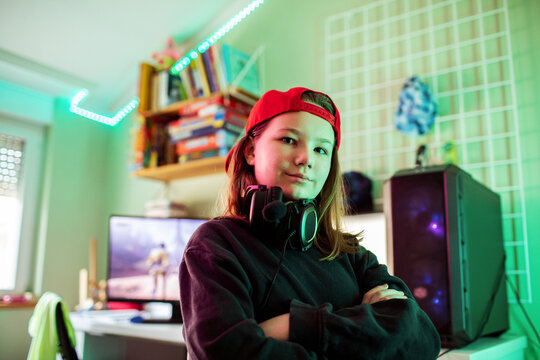 Confident teenage gamer with headset in rgb-lit bedroom