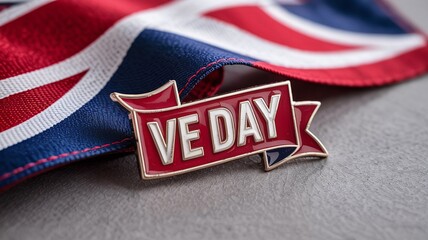 VE Day Commemorative Enamel Pin Badge Resting on a British Union Jack Flag Background to Honor and Remember World War Two Heroes