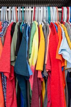 Colorful Assorted T-Shirts Neatly Hanging on Closet Rack in Organized Wardrobe