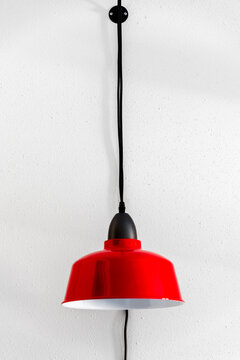 Red Industrial Pendant Light Suspended in Front of White Textured Wall