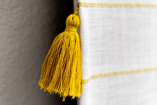 Mustard Yellow Cotton Tassel Detail on White Woven Fabric Close Up
