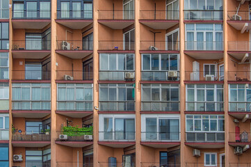 Background with a sienna-colored facade of a residential building with square balconies on a street in Madrid, Spain.