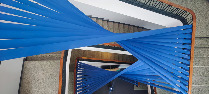 A multi-level staircase interior with bright blue ribbon-like elements. A concept for contemporary architecture and a creative installation in an urban building. - Powered by Adobe