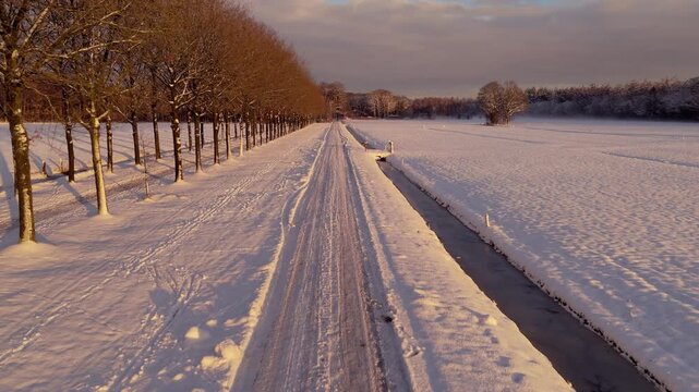 Drone Following Road Through Snowy Meadows