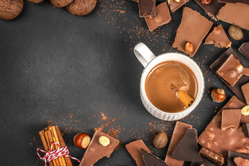 Hot chocolate with cinnamon and chocolate pieces on dark background with copy space