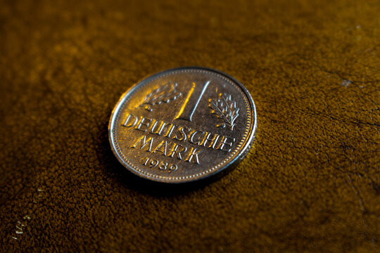 one old shiny silver colored deutschmark coin laying on a wooden underground