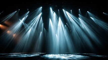 A dark stage illuminated by multiple bright spotlights shining down from above