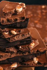Stack of chocolate pieces with nuts close up on dark background