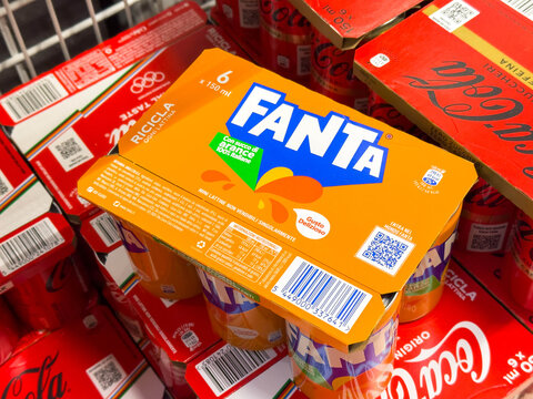 Tarvisio, Italy - January 15, 2026: Fanta soda packaging displayed on top of Coca-Cola cans in a grocery store, showcasing vibrant colors and branding in a retail environment