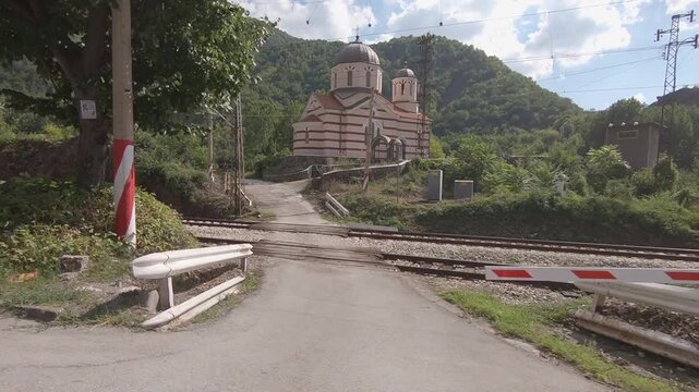 Video filmed from a moving car showing St. Prophet Elisha Church in Eliseyna village near Mezdra, with the railway line visible alongside the rural landscape, BG 01 Aug. 2019