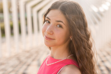 Obraz premium beautiful teenage brunette girl with long hair, smiling, looking at the camera during a summer walk
